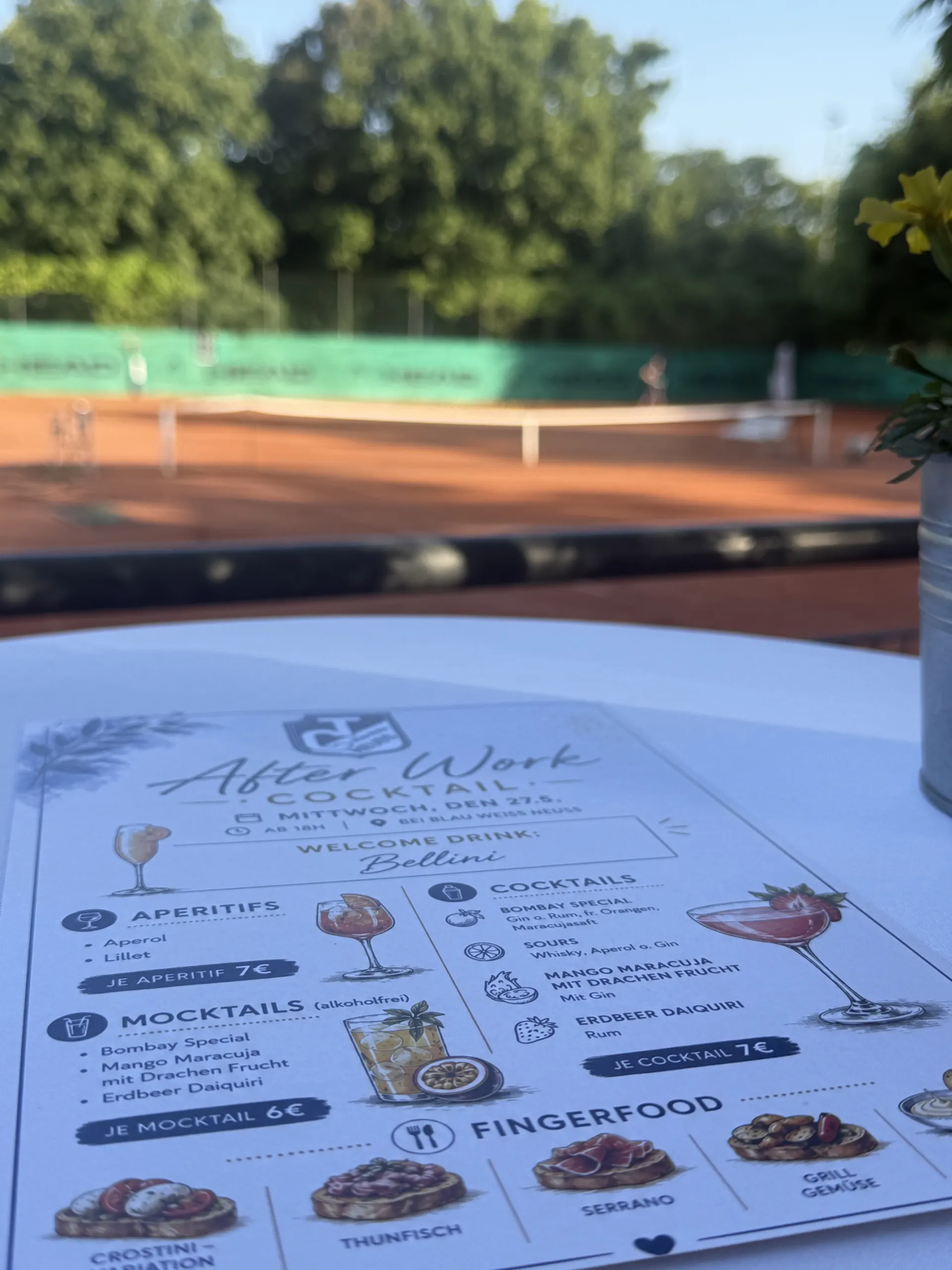 Cocktailkarte des After-Work-Abends auf einem Stehtisch, im Hintergrund die Tennisplätze